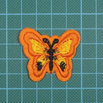 Patch bordado em forma de borboleta laranja e amarela sobre fundo azul quadriculado