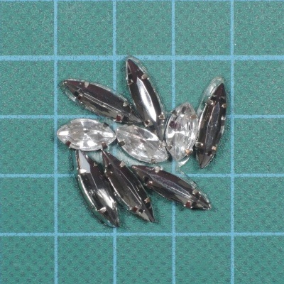 Cristais de vidro transparentes e fumados em formato oval e navete sobre superfície verde quadriculada