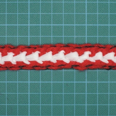 Cordão trançado vermelho e branco sobre superfície verde quadriculada