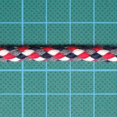 Cordão trançado vermelho, branco e azul sobre superfície verde quadriculada