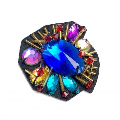 Broche com pedras coloridas e detalhes dourados sobre base preta