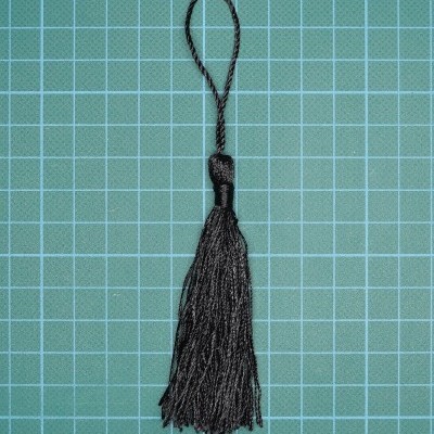 Borra preta com laço torcido sobre fundo quadriculado verde