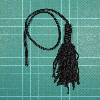 Franja ou cordão preto trançado sobre fundo verde com grelha branca
