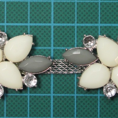 Bracelete com flores em tons nude e pedras brilhantes sobre fundo de rede verde