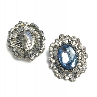 Botões metálicos prateados decorativos com pedras azuis e cristais.