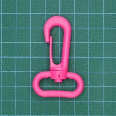 Gancho mosquetão de plástico rosa sobre fundo verde quadriculado