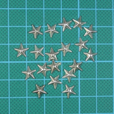 Estrelas metálicas pequenas prateadas em superfície verde quadriculada