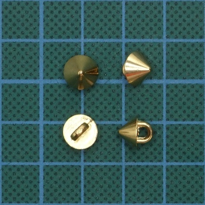 Tachas metálicas douradas em formato de cone sobre fundo verde quadriculado