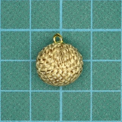 Pingente redondo de tecido trançado bege claro com argola dourada sobre fundo verde em grelha