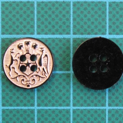 Dois botões redondos, um dourado com relevo e um preto liso, sobre superfície de grade