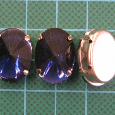 Três botões ovais azul escuro com moldura dourada sobre superfície quadriculada verde