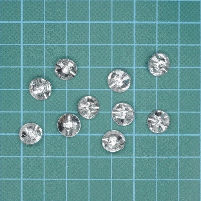 Dez botões transparentes em superfície verde com grade azul.