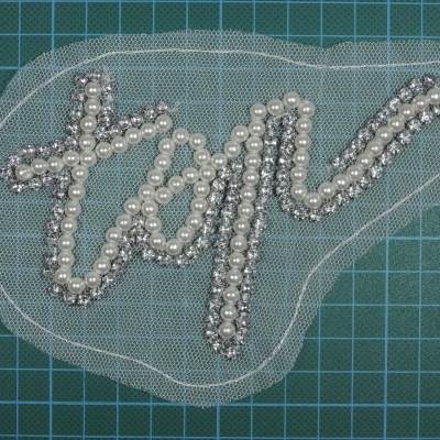 Aplicação de tecido com a palavra 'top' em contas sobre fundo de grelha azul