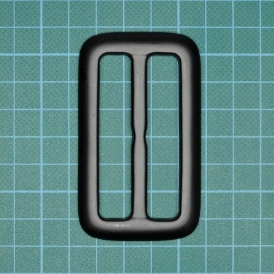 Prendedor de plástico preto retangular sobre superfície verde quadriculada