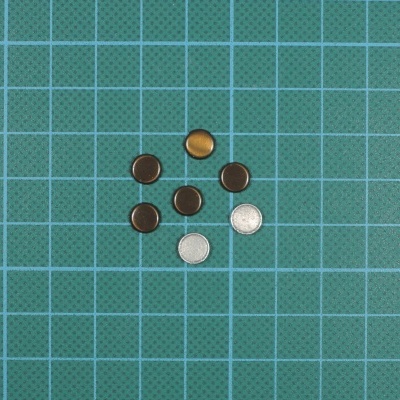 Set de pilhas pequenas redondas sobre superfície verde quadriculada