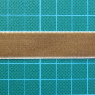 Fita de veludo castanha com bordas brancas sobre superfície azul quadriculada