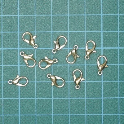 Dez fechos de lagosta dourados para bijuteria em fundo verde quadriculado
