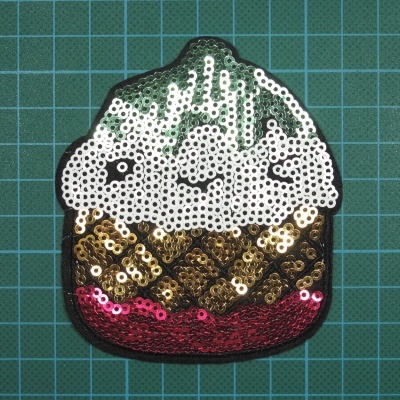 Aplicação de cupcake com lantejoulas sobre superfície quadriculada verde