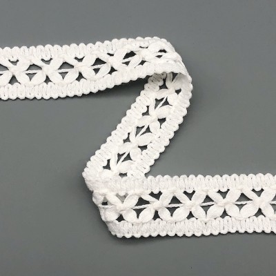 Renda branca de algodão com padrão decorativo colocada sobre fundo cinza