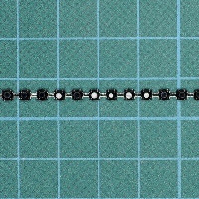 Fita LED preta com pequenos LEDs brancos sobre base verde quadriculada