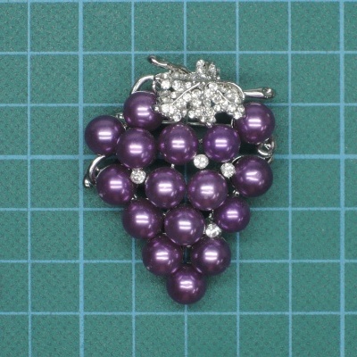 Broche forma uva pérolas roxas detalhes brilhantes prateados fundo verde