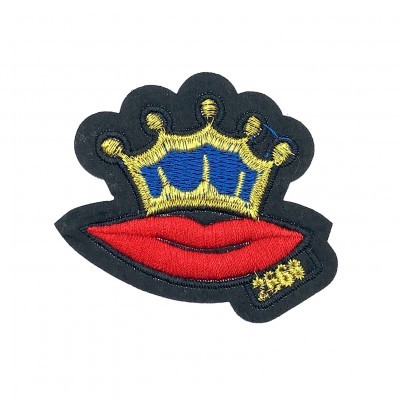 Emblema bordado com coroa amarela e azul e lábios vermelhos sobre fundo preto