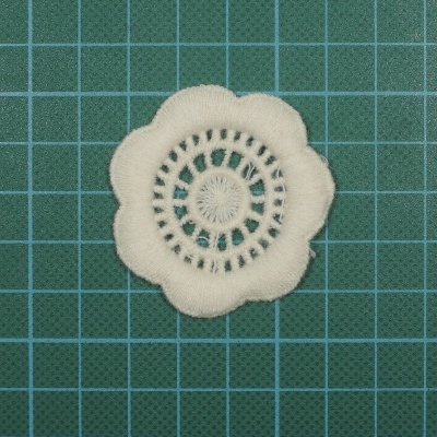 Aplicação decorativa branca em tecido sobre base verde quadriculada