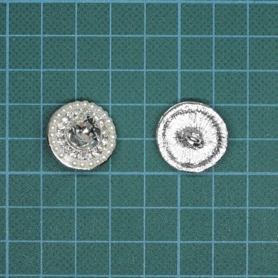 Dois botões prateados redondos sobre fundo verde com grade branca