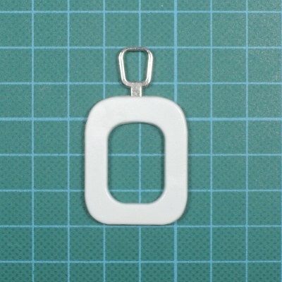 Pingente oval branco com argola metálica sobre fundo quadriculado azul