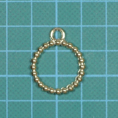 Pingente circular dourado com argola sobre superfície com padrão de grade azul