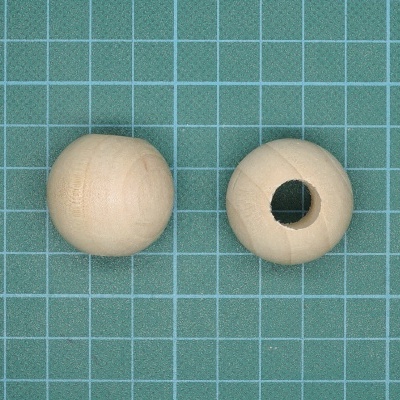 Duas contas esféricas de madeira clara sobre superfície verde com grelha branca.