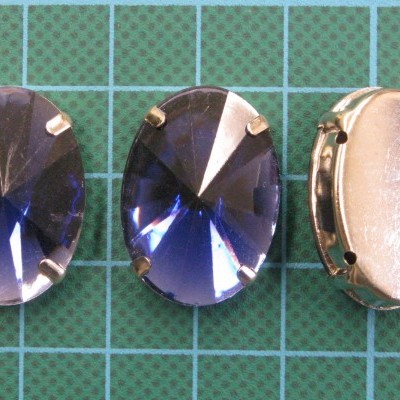 Três botões ou pedras azuis ovais com engate metálico em base quadriculada verde