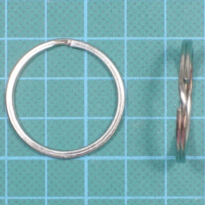 Par de argolas de metal prateado sobre fundo azul quadriculado