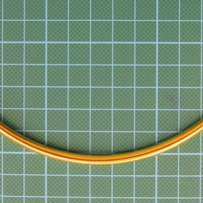 Mola metálica fina amarela curva sobre superfície quadriculada verde