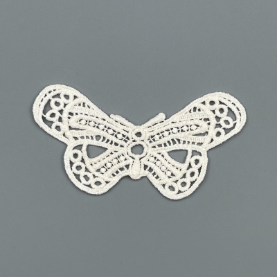 Aplicação em renda branca em forma de borboleta sobre fundo cinzento.