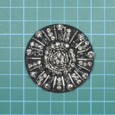 Botão decorativo redondo com cristais brilhantes sobre fundo quadriculado azul