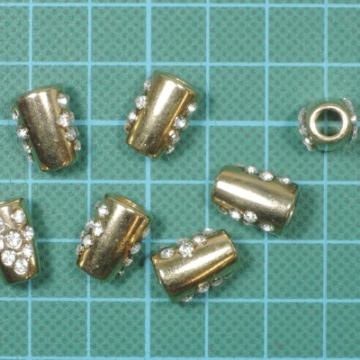 Contas metálicas cilíndricas com pedras brilhantes sobre fundo quadriculado azul esverdeado