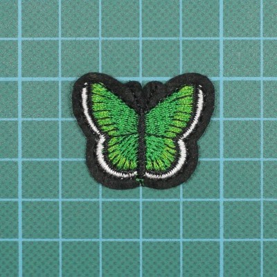 Patch bordado de borboleta verde com contorno preto sobre fundo quadriculado azul