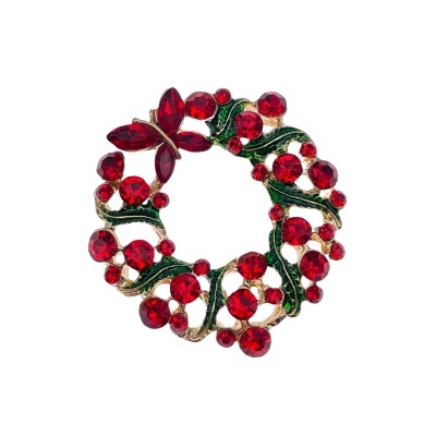 Broche em forma de coroa de Natal com pedras vermelhas e detalhes verdes em fundo branco