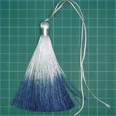 Borla de seda branca a azul sobre superfície quadriculada verde