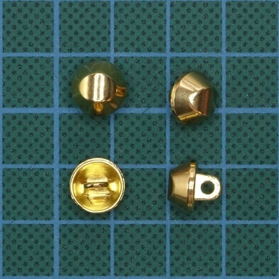 Peças metálicas douradas semi-esféricas sobre superfície verde com grelha azul