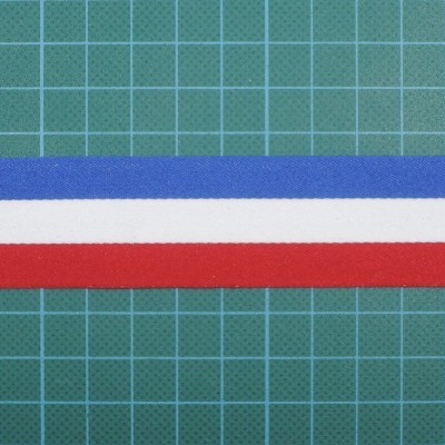 Fita tricolor azul, branco e vermelho sobre superfície verde quadriculada