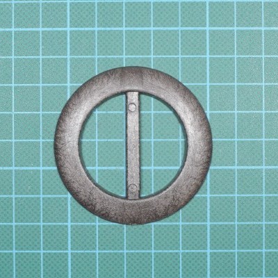 Fivela redonda em metal sobre superfície quadriculada verde