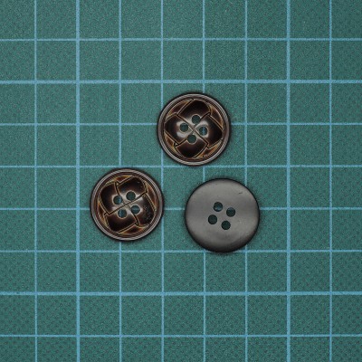 Três botões redondos pretos com quatro furos sobre superfície de grade azul