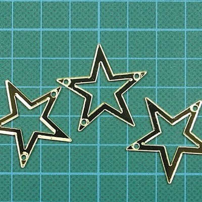 Pendentes metálicos em forma de estrelas prateadas em superfície quadriculada verde