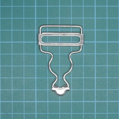 Clip metálico prateado sobre superfície verde com padrão de grade branca