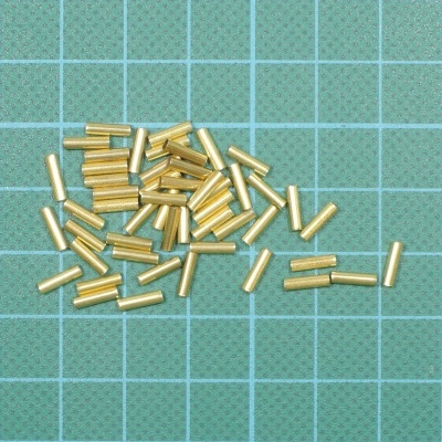 Pequenos tubos metálicos dourados sobre superfície verde quadriculada