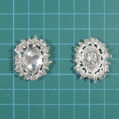 Par de botões prateados com base oval facetada e aro decorativo recortado