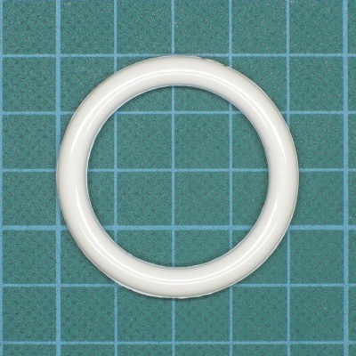 Anel circular branco de plástico sobre superfície verde com grelha