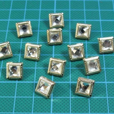 Botões quadrados transparentes com moldura dourada sobre base de corte verde